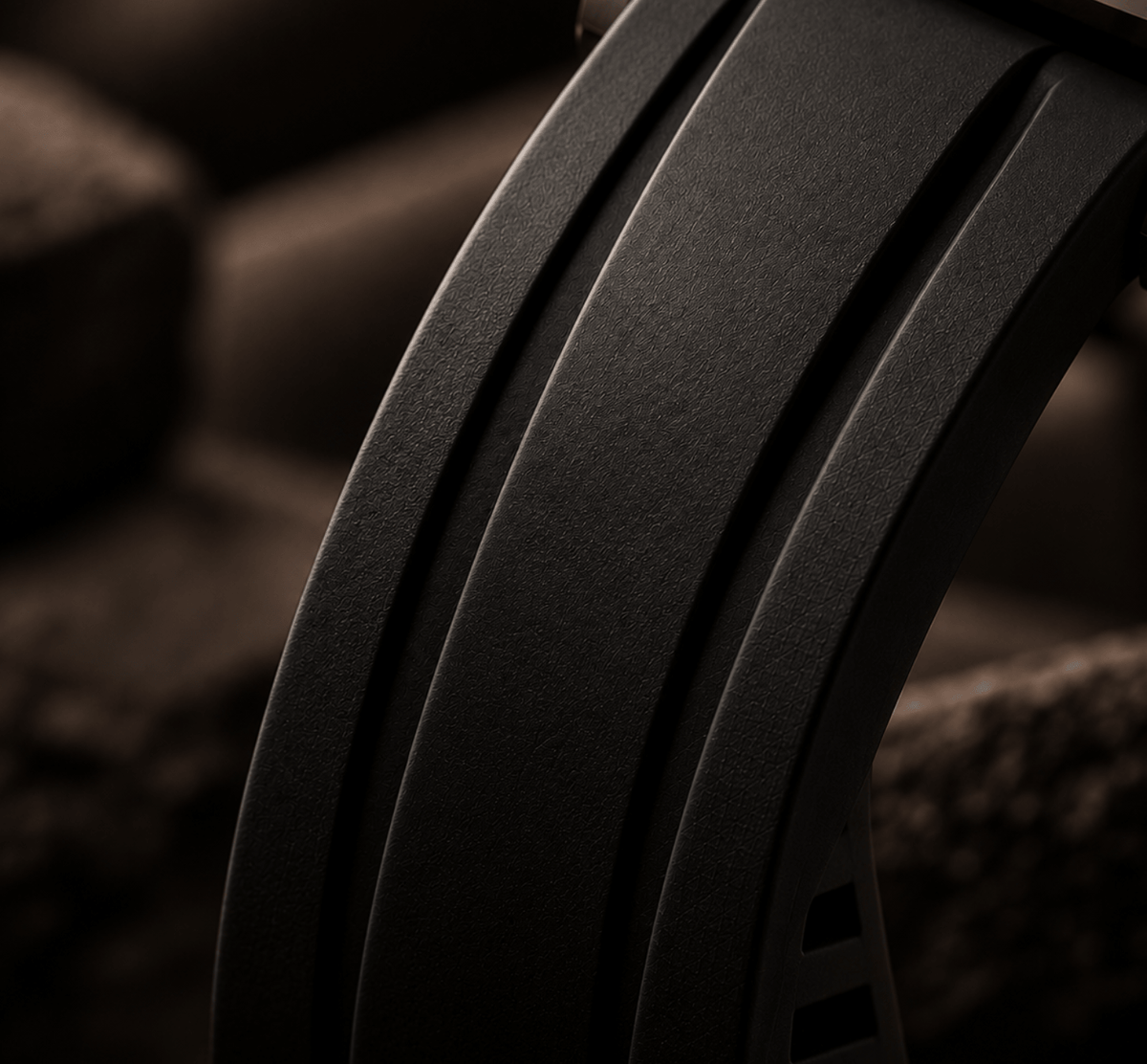 Close-up of a dark textured curved product, likely a strap or band, with three parallel ridges and a soft warm brown background.