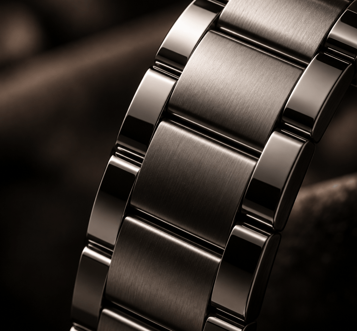Close-up of a polished stainless steel link bracelet with brushed and polished metallic surfaces, set against a dark, blurred background.