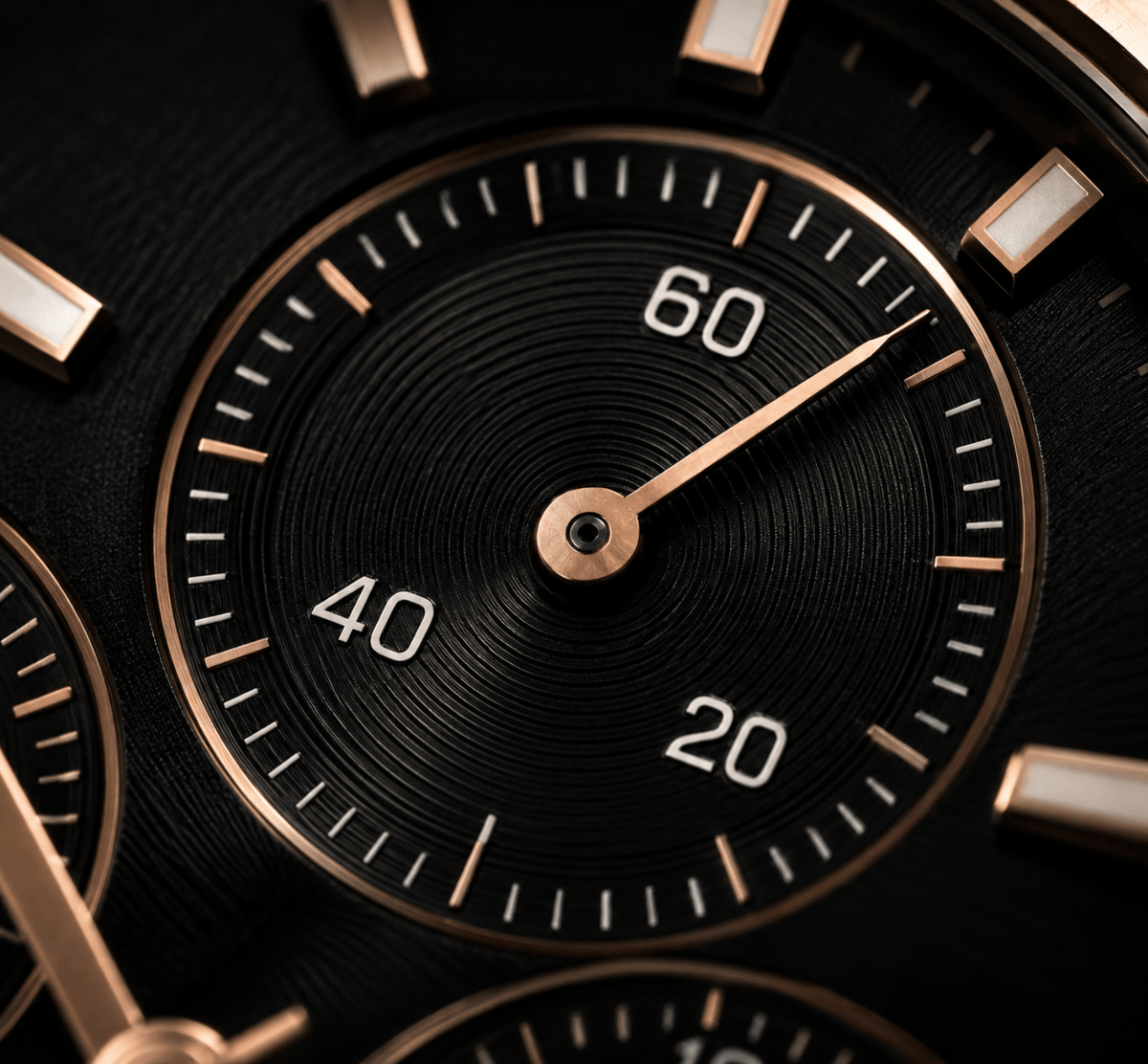 Close-up of a luxury watch dial with a black textured center, rose gold markers and hands, and white numerals on a dark background.