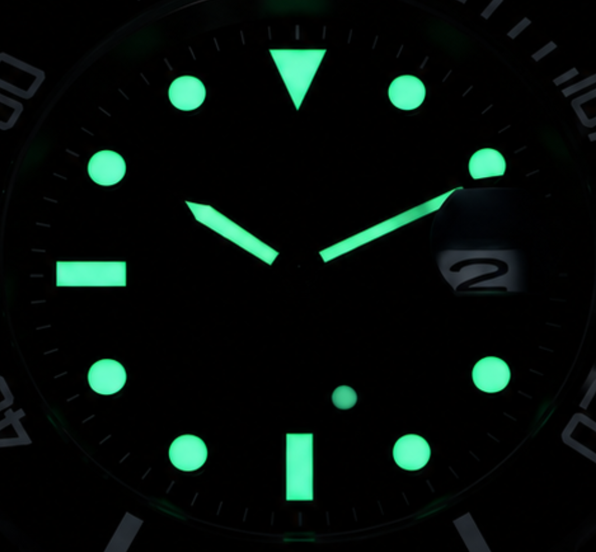 Luminous watch dial in black, showing bright green hour markers, hands, and a date window at 2.